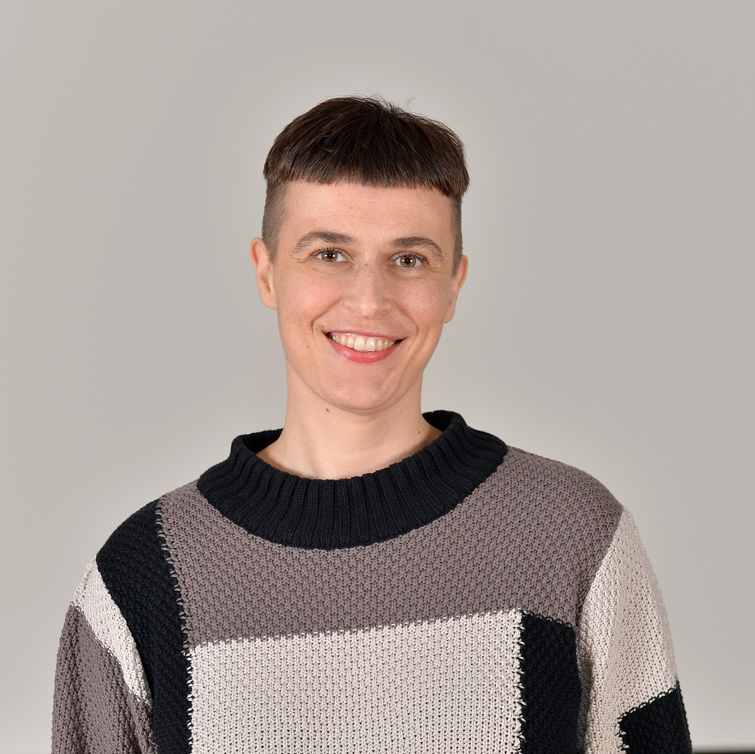 Das Bild zeigt Dr. Eni Depping, eine Person mit kurzen dunklen Haaren und einem Strickpullover.